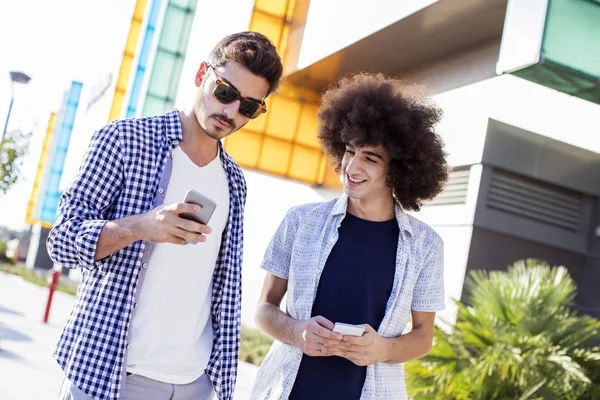 Молодые люди используют мобильный телефон на улице — стоковое фото