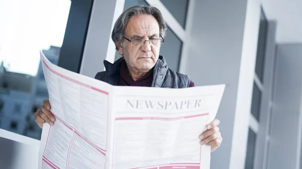 年配の男性が屋外で新聞を読む — ストック写真