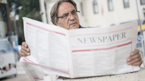 Starszy człowiek czytanie gazety w na zewnątrz — Zdjęcie stockowe