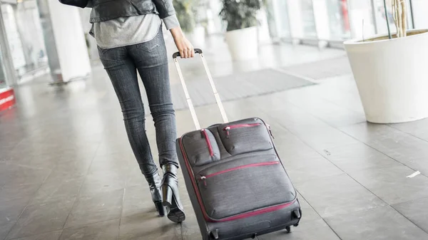 Пассажир, идущий в аэропорт с чемоданом — стоковое фото