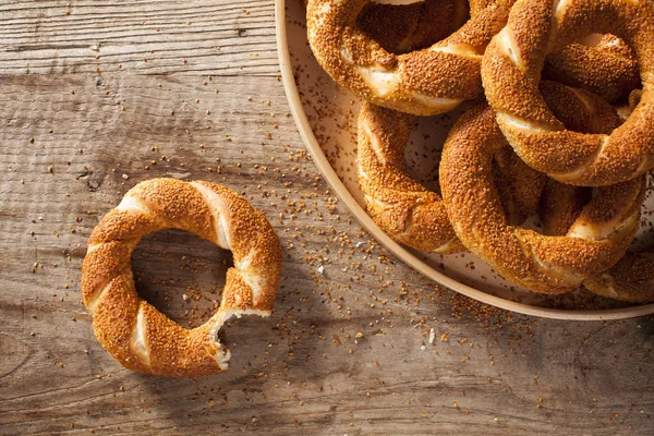 Pile Turkish bagel Simit in a plate  and bitten bagel on wooden background