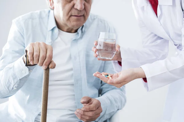 Elderly ill man and nurse giving medicine