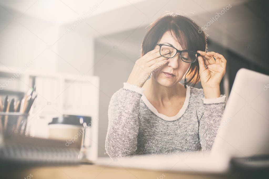 Tired middle age woman rubbing eyes 