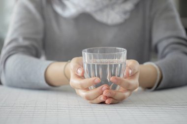 Genç bir kadın elinde bir bardak su tutuyor.