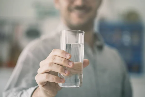 Jovem feliz segurando vidro de água dentro — Fotografia de Stock