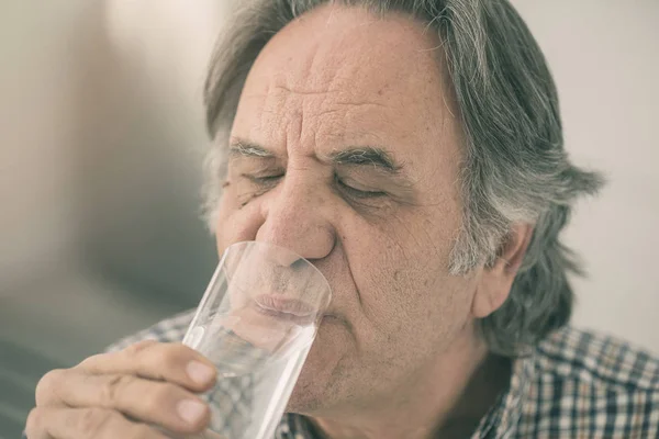 Senior homme boire un verre d'eau à l'intérieur — Photo