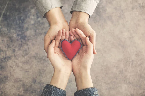 Man och kvinna händer tillsammans med rött hjärta — Stockfoto