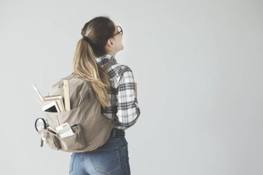 Gri arka plan üzerinde sırt çantası ile kız öğrenci
