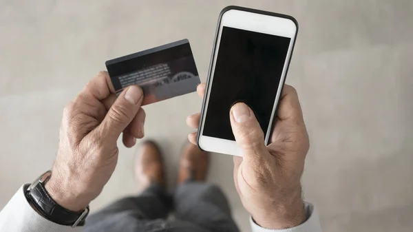 Man using credit card and mobile phone