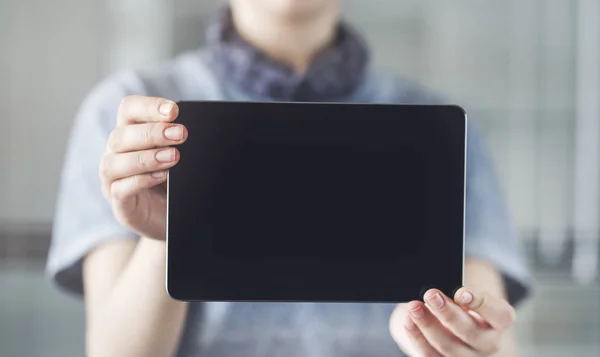 Woman holding and showing black digital tablet