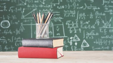 Yeşil tebeşir tahtası önünde kalemler ile kitapları