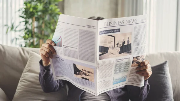 Senior man reading newspaper at home