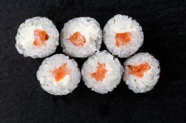 Siyah arka planda somon balıklı Maki Suşi Rolls. Suşi menüsü. Japon yemeği. Sushi dürümlü lezzetli Japon yemeklerini yakından çek. Yatay fotoğraf