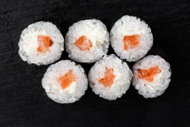 Siyah arka planda somon balıklı Maki Suşi Rolls. Suşi menüsü. Japon yemeği. Sushi dürümlü lezzetli Japon yemeklerini yakından çek. Yatay fotoğraf