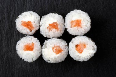 Siyah arka planda somon balıklı Maki Suşi Rolls. Suşi menüsü. Japon yemeği. Sushi dürümlü lezzetli Japon yemeklerini yakından çek. Yatay fotoğraf