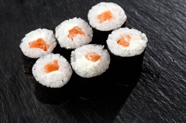 Siyah arka planda somon balıklı Maki Suşi Rolls. Suşi menüsü. Japon yemeği. Sushi dürümlü lezzetli Japon yemeklerini yakından çek. Yatay fotoğraf