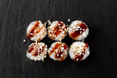 Maki suşi ruloları, siyah arka planda siyah kayanın üzerinde yılan balığı. Suşi menüsü. Japon yemeği. Sushi dürümlü lezzetli Japon yemeklerini yakından çek. Yatay fotoğraf