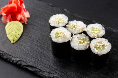 Salatalıklı Maki Suşi Rolls ya da siyah arka planda siyah taşlı avokado. Suşi menüsü. Japon yemeği. Sushi dürümlü lezzetli Japon yemeklerini yakından çek. Yatay fotoğraf