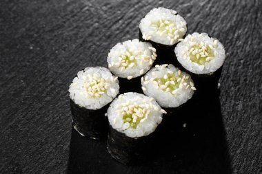 Salatalıklı Maki Suşi Rolls ya da siyah arka planda siyah taşlı avokado. Suşi menüsü. Japon yemeği. Sushi dürümlü lezzetli Japon yemeklerini yakından çek. Yatay fotoğraf
