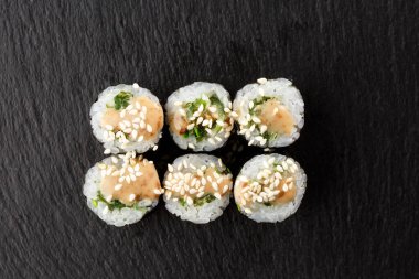 Wakame ve fındık soslu Maki Suşi Rolls. Siyah arka planda. Suşi menüsü. Japon yemeği. Sushi dürümlü lezzetli Japon yemeklerini yakından çek. Yatay fotoğraf
