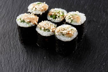 Wakame ve fındık soslu Maki Suşi Rolls. Siyah arka planda. Suşi menüsü. Japon yemeği. Sushi dürümlü lezzetli Japon yemeklerini yakından çek. Yatay fotoğraf