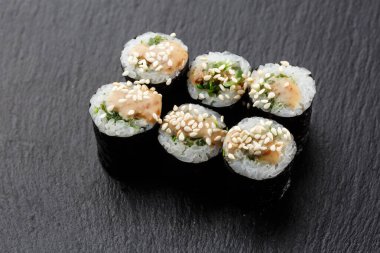 Wakame ve fındık soslu Maki Suşi Rolls. Siyah arka planda. Suşi menüsü. Japon yemeği. Sushi dürümlü lezzetli Japon yemeklerini yakından çek. Yatay fotoğraf