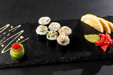 Wakame ve fındık soslu Maki Suşi Rolls. Siyah arka planda. Suşi menüsü. Japon yemeği. Sushi dürümlü lezzetli Japon yemeklerini yakından çek. Yatay fotoğraf