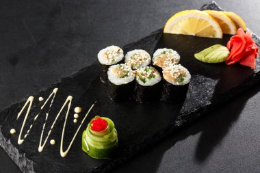 Wakame ve fındık soslu Maki Suşi Rolls. Siyah arka planda. Suşi menüsü. Japon yemeği. Sushi dürümlü lezzetli Japon yemeklerini yakından çek. Yatay fotoğraf