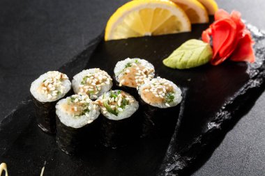 Wakame ve fındık soslu Maki Suşi Rolls. Siyah arka planda. Suşi menüsü. Japon yemeği. Sushi dürümlü lezzetli Japon yemeklerini yakından çek. Yatay fotoğraf