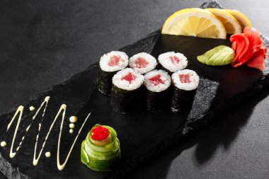 Siyah arka planda ton balıklı Maki suşi ruloları. Suşi menüsü. Japon yemeği. Sushi dürümlü lezzetli Japon yemeklerini yakından çek. Yatay fotoğraf