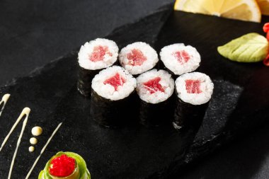 Siyah arka planda ton balıklı Maki suşi ruloları. Suşi menüsü. Japon yemeği. Sushi dürümlü lezzetli Japon yemeklerini yakından çek. Yatay fotoğraf