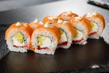 İçinde somon, avokado, uçan balık havyarı ve krem peynirli suşi ruloları var. Somonlu Philadelphia suşisi. Suşi menüsü. Yatay fotoğraf.