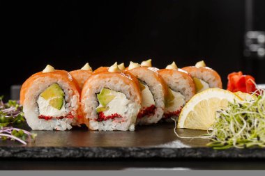 İçinde somon, avokado, uçan balık havyarı ve krem peynirli suşi ruloları var. Somonlu Philadelphia suşisi. Suşi menüsü. Yatay fotoğraf.