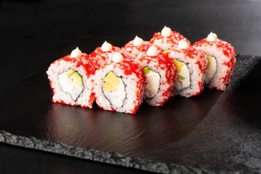 İçinde avokado, karides ve krem peynirli suşi ruloları var. Kaliforniya dürümleri turuncu tobiko ya da masago havyarı ile kaplıdır. Suşi menüsü. Yatay fotoğraf.