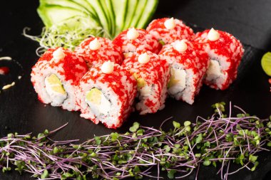 İçinde avokado, karides ve krem peynirli suşi ruloları var. Kaliforniya dürümleri turuncu tobiko ya da masago havyarı ile kaplıdır. Suşi menüsü. Yatay fotoğraf.