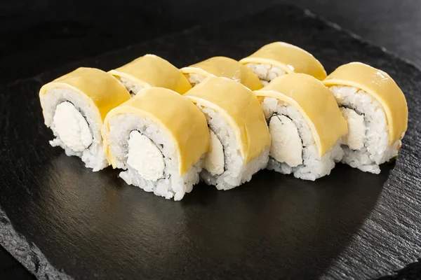 Sushi Rolls with processed cheese, cheddar, american cheese and Cream Cheese inside on black slate isolated. Philadelphia roll sushi with shrimp. Sushi menu. Horizontal photo.