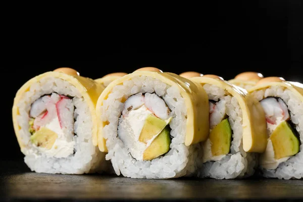 Sushi Rolls with processed cheese, cheddar, american cheese, avocado, crab meat, shrimp and Cream Cheese inside on black slate isolated. Philadelphia roll sushi with shrimp. Sushi menu. Horizontal.
