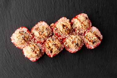 İçinde avokado, yılan balığı, salatalık ve krem peynirli suşi rulosu ve siyah tahtada ton balığı sosu var. Kaliforniya dürümleri turuncu tobiko ya da masago havyarı ile kaplıdır. Suşi menüsü. Yatay fotoğraf.