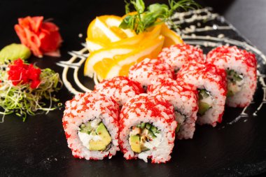 İçinde avokado, yılan balığı, salatalık ve krem peynirli suşi ruloları var. Kaliforniya dürümleri turuncu tobiko ya da masago havyarı ile kaplıdır. Suşi menüsü. Yatay fotoğraf.