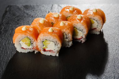 İçinde somon, avokado, uçan balık havyarı ve krem peynirli suşi ruloları var. Somonlu Philadelphia suşisi. Suşi menüsü. Yatay fotoğraf.
