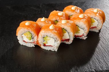 İçinde somon, avokado, uçan balık havyarı ve krem peynirli suşi ruloları var. Somonlu Philadelphia suşisi. Suşi menüsü. Yatay fotoğraf.