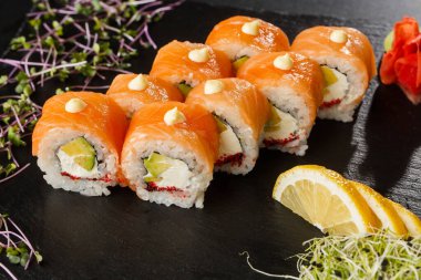 İçinde somon, avokado, uçan balık havyarı ve krem peynirli suşi ruloları var. Somonlu Philadelphia suşisi. Suşi menüsü. Yatay fotoğraf.