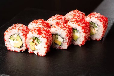 İçinde avokado, yılan balığı, salatalık ve krem peynirli suşi ruloları var. Kaliforniya dürümleri turuncu tobiko ya da masago havyarı ile kaplıdır. Suşi menüsü. Yatay fotoğraf.