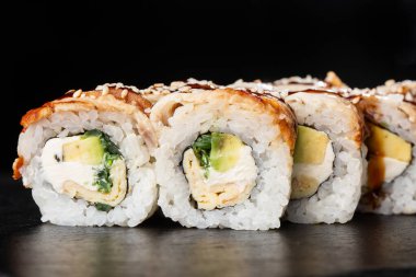 İçinde salatalık, avokado, yılan balığı, omlet ve krem peynirli suşi ruloları var. Philadelphia unagi suşisi ve tamago. Suşi menüsü. Yatay fotoğraf.