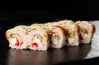 İçinde salatalık, uçan balık havyarı, yılan balığı, omlet ve krem peynirli suşi ruloları var. Philadelphia unagi suşisi ve tamago. Suşi menüsü. Yatay fotoğraf.