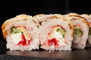 İçinde salatalık, uçan balık havyarı, yılan balığı, omlet ve krem peynirli suşi ruloları var. Philadelphia unagi suşisi ve tamago. Suşi menüsü. Yatay fotoğraf.
