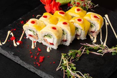 İçinde salatalık, çedar, uçan balık havyarı, ton balığı ve krem peynirli suşi ruloları var. Philadelphia peynirli suşi ve ton balığı. Suşi menüsü. Yatay fotoğraf.