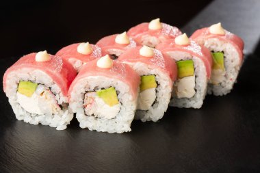 İçinde avokado, ton balığı, karides, yengeç eti ve krem peynirli suşi ruloları var. Philadelphia suşisi ve ton balığı. Suşi menüsü. Yatay fotoğraf.