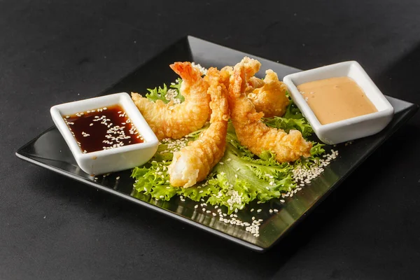 Tempura Deep Fried Shrimp Ebi with sweet chili and soy sauce on black board stone on dark background. Japanese food style appetizer. Deep fried prawn in breeding close up. Horizontal photo.