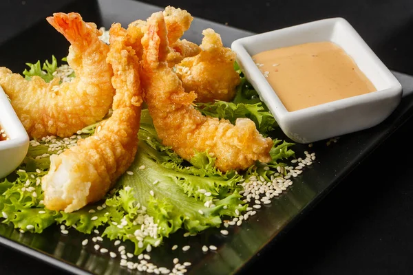 Tempura Koyu Kızarmış Karides Ebi, acı biberli ve soya soslu, siyah tahta taşlı, siyah arka planda. Japon yemek tarzı aperatif. Kızarmış karidesi yakından çiftleştirmek. Yatay fotoğraf.